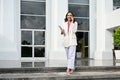 Professional Asian female boss walking out of the building while talking on the phone Royalty Free Stock Photo