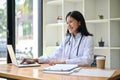 A professional Asian female doctor working and reading medical cases on her laptop at her desk Royalty Free Stock Photo