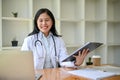 A professional Asian female doctor working and reading medical cases on her laptop at her desk Royalty Free Stock Photo