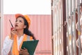 Professional asian female workerusing walkie-talkie in shipping yard industrial container box from cargo freight ship for import Royalty Free Stock Photo