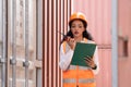Professional asian female workerusing walkie-talkie in shipping yard industrial container box from cargo freight ship for import Royalty Free Stock Photo