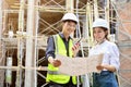 Asian male engineer and female architect are looking and holding a blueprint Royalty Free Stock Photo