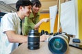 Professional young asian male and female photographers are smiling, sitting on the desk full of lens, and  camera in the modern Royalty Free Stock Photo