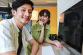 Professional young asian male and female photographers are smiling, sitting on the desk full of lens, and  camera in the modern Royalty Free Stock Photo