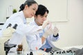 A professional Asian middle-aged female scientist training and inspecting a young male scientist