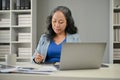 A professional Asian senior female boss focuses on her business work at her desk Royalty Free Stock Photo