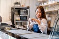 Professional Asian woman Barista preparing coffee at front counter serving coffee cup