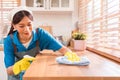 Professional Asian woman cleaning service wearing yellow rubber gloves, using a rag to wipe with spraying liquid detergent. Royalty Free Stock Photo