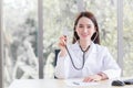 Professional Asian woman doctor wears medical coat and stethoscope in office room while looking at the camera at hospital with Royalty Free Stock Photo