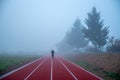 Professional athlete train at athletics running track in morning blue mist. Sport photo, edit space