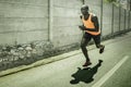 Professional athlete training - young fit and athletic black african american man doing urban running workout on asphalt road