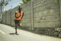 Professional athlete training - young fit and athletic black african american man doing urban running workout on asphalt road