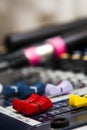 Professional audio mixer with colorful faders, microphones lying in the blurred background Royalty Free Stock Photo