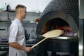 Professional baker chef making traditional italian pizza in oven