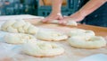 Professional baker is forming pieces of dough in bakery commercial kitchen.