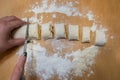 professional baker with knife cuts the raw sausage dough into even small pieces