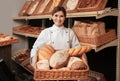 Professional baker with tray full of breads in store