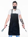 Professional barbecue. Bearded man with barbecue fork and spatula in hands. Grill cook using portable barbecue cooking