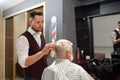 Professional barber grooming man`s hair in barbershop.