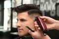 Professional barber making stylish haircut in salon