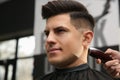 Professional barber making stylish haircut in salon, closeup