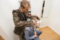 Professional barber shaving male customer's hair in shop