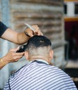 Professional barber styling hair receiving haircut using Hair cu