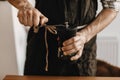 Professional barista in black stylish apron grinding coffee for aeropress, alternative brewing method. Hands holding manual