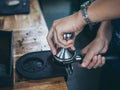 Professional barista hands pressing coffee grounds with tamper in cafe