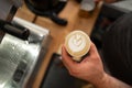 Professional barista holding paper cup with latte foam over coffee, espresso and creating a perfect cappuccino Royalty Free Stock Photo