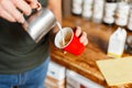 Professional barista makes coffee in her vintage coffee shop. Man pours coffee from a metal cup into a red cup. Close-up