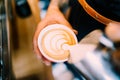 Professional barista pouring latte foam over coffee, espresso and creating a perfect cappuccino