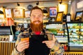 Professional barista young redhaired ginger bearded man in black apron working in coffee shop