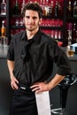 Professional barman in black standing bar