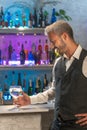 Professional barman tasting cocktail in nightclub. Night life concept. Vertical photo.