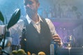 Professional barman in a white shirt and black apron making cocktail at party in a tropical nightclub. Nightlife concept Royalty Free Stock Photo