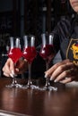 Professional bartender arranging a colorful selection of red cocktails on a wooden counter Royalty Free Stock Photo