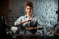 Professional bartender girl holds metal shaker at bar