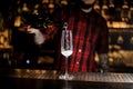 Professional bartender pourring a champagne from a bottle to a g