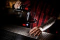 Professional bartender pourring a red wine from a bottle to a glass
