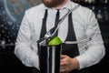 Professional bartender squeeze lime juice with an iron tool with a juicer into a metal shaker, close-up Royalty Free Stock Photo