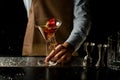 Professional bartender throwing a red rose bud to a martini glass with a cocktail Royalty Free Stock Photo