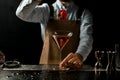 Professional bartender throwing a red rose bud to a martini glass with a golden cocktail Royalty Free Stock Photo