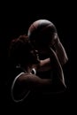 Professional basketball player holding a ball against black background. Serious concentrated african american man in sports