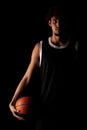 Professional basketball player holding a ball against black background. Serious concentrated african american man in sports Royalty Free Stock Photo