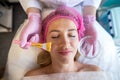 professional beautician applies a golden healing mask to a woman& x27;s face.