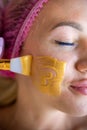 professional beautician applies a golden healing mask to a woman& x27;s face.