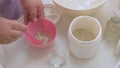 Professional beautician mixes the ingredients in a pink cup. Close-up. Preparation of anti-aging mask of algae. Health and beauty