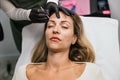 Professional beautician prepares client& x27;s eyebrows with precise design before microblading, emphasizing careful makeup work Royalty Free Stock Photo