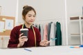 Asian female fashion designer working with fabric sketches and drawing clothing design at the studio. Royalty Free Stock Photo